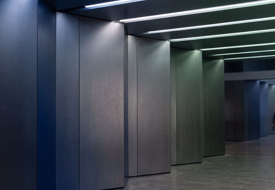 Abstract corporate architectural wall illuminated by clean spectrum of dark navy blue, slate charcoal and deep sage green light bands.